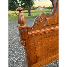 a wooden bed frame with an ornate carved headboard and foot board on gravel ground