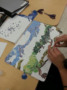 a person is working on some art work at a table with scissors and other items