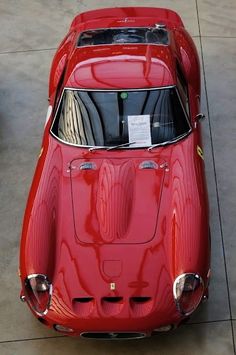 an old red sports car parked in a garage