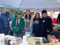 four people standing under a tent at an outdoor market