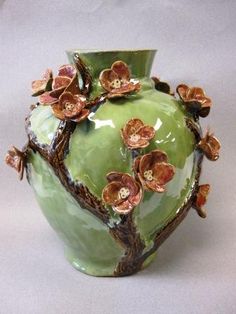 a green vase with brown flowers on it