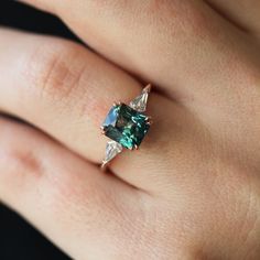 a woman's hand with a ring on it and an emerald stone in the middle