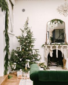 a living room decorated for christmas with green couches and white stockings on the mantel