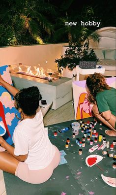 two women are sitting on the floor painting