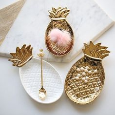 three pineapple shaped brooches sitting next to each other on a marble surface