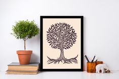 an art print with a tree on it next to some books and a potted plant