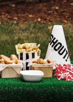 a table topped with boxes filled with donuts next to a white cone shaped sign