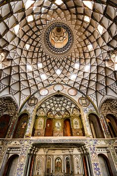 the inside of an ornate building with stained glass and metalwork on the ceiling, looking up