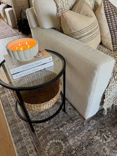 a living room with a couch, coffee table and books on the end table in front of it