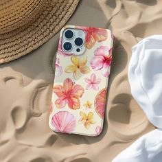 an iphone case sitting on top of sand next to a straw hat and sunhat