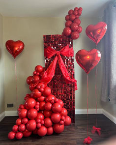 red balloons are arranged in the shape of a pyramid and heart - shaped balloons with ribbons on them