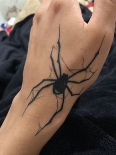 a person's hand with a spider tattoo on it