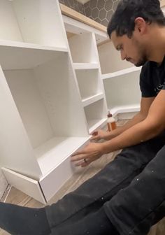 a man sitting on the floor in front of some shelves