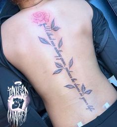 the back of a woman's lower back tattoo with flowers and words on it