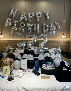 a birthday party with balloons and gifts on the bed in front of a large sign that says happy birthday