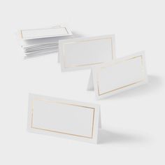 white and gold place cards on top of each other in front of a gray background