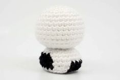 a small crocheted white and black object sitting on top of a white surface