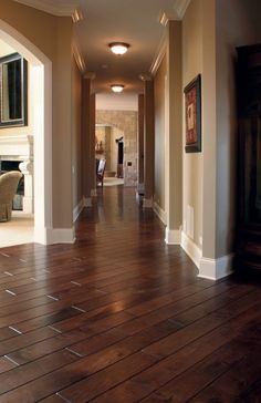 an empty hallway with wood floors and paintings on the wall