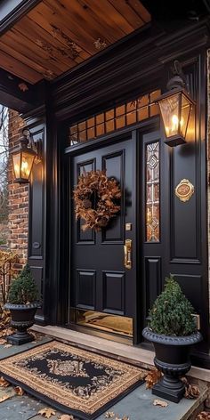 a black front door with two lights and a rug on the ground next to it