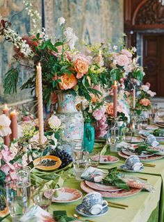 the table is set with plates and flowers in vases, candles, and dishes