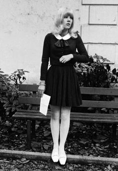 a woman standing next to a wooden bench