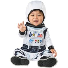 a baby dressed in an astronaut costume sitting on the ground with his hands up and mouth wide open