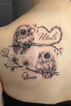 an owl tattoo on the back of a woman's shoulder with two owls sitting on a branch