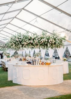 a table with flowers and bottles on it under a tented area for an event