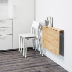 two white chairs and a wooden table in a room