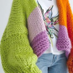 a woman wearing colorful knitted sweaters and jeans