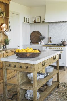 a bowl of lemons sits on top of a wooden island in the middle of a kitchen