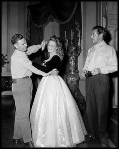 an old black and white photo of a man adjusting a woman's dress