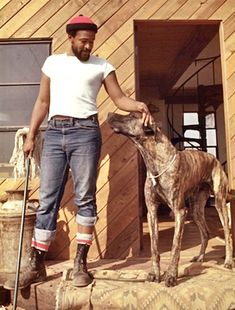 a man standing next to a dog on top of a pile of dirt near a building