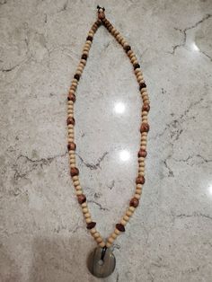 a wooden beaded necklace with a metal hook hanging from it's end on a marble surface