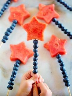 a hand holding a piece of watermelon and blue beads with stars on it