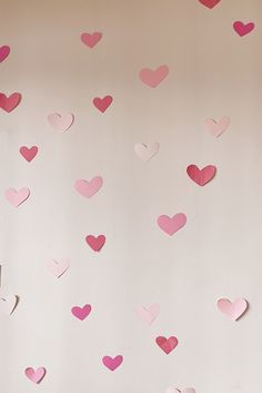 pink and red hearts hanging from the ceiling in a room with wall paper on it