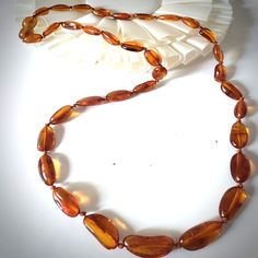 This natural amber bead necklace is suitable for men and women. Crafted by hand with the knotting between each bead. The necklace has a small plastic screw clasp. The clasp has a cognac color, like a necklace, and makes it almost invisible. Necklace size: 16-17 inch Bead color: cognac Bead shape: oval free-form Bead size: approximately 10mm long 4mm in diameter Cord: cotton ATTN: The color of Baltic Amber may vary from necklace to necklace due to each necklace being hand made from natural materi Affordable Amber Necklace For Gifts, Cheap Amber Necklaces For Gifts, Luxury Amber Oval Beaded Necklace, Luxury Amber Oval Necklaces, Beads Necklace For Men, Invisible Necklace, Amber Bead Necklace, Free Shapes, Cognac Color