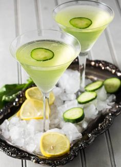 two glasses filled with lemon cucumber martini on top of ice