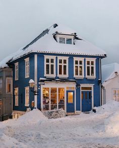 a blue house with snow on the ground and stairs leading up to it's windows