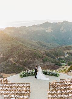 a bride and groom standing in front of their wedding ceremony set up at the top of a mountain