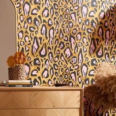 a leopard print wallpaper with pink and black designs on the walls next to a dresser