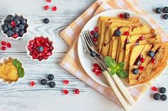 blueberries, raspberries and other berries are on a plate with silverware