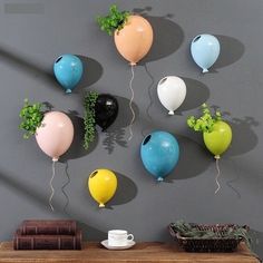 several balloons are hanging on the wall above a table with books and coffee mugs