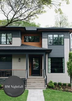 a large gray house with lots of windows and stairs leading to the front door area