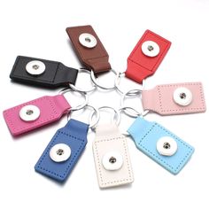 six different colored leather keychains with buttons in the middle and one has a button on it