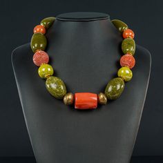 23" unusual Olive green Agate ovals (25x40mm) offset with orange sponge Cor( 25mm) orange Ceramic and Bamboo cylinders. Lime green Ceramic beads add that touch of Fall to the general feeling.  The beads are separated with African Brass rondels, gold metal rondels and the clasp is a 38mm round lined flat bronze coloured toggle. Fall Necklaces, Bamboo Necklace, Chalcedony Bracelet, Orange Ceramic, Wearable Art Jewelry, Pearl Necklace Designs, Jewelry Making Earrings, Beaded Jewelry Designs, Chunky Jewelry