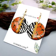 a pair of orange and black earrings on top of a card