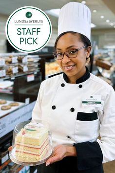 a woman holding a cake in front of a sign that says staff pick on it