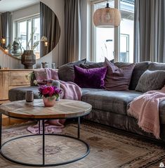 a living room filled with furniture and a large mirror on the wall above it's windows