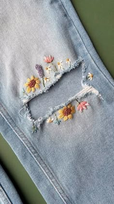 an old pair of jeans with embroidered flowers on the side and holes in the back